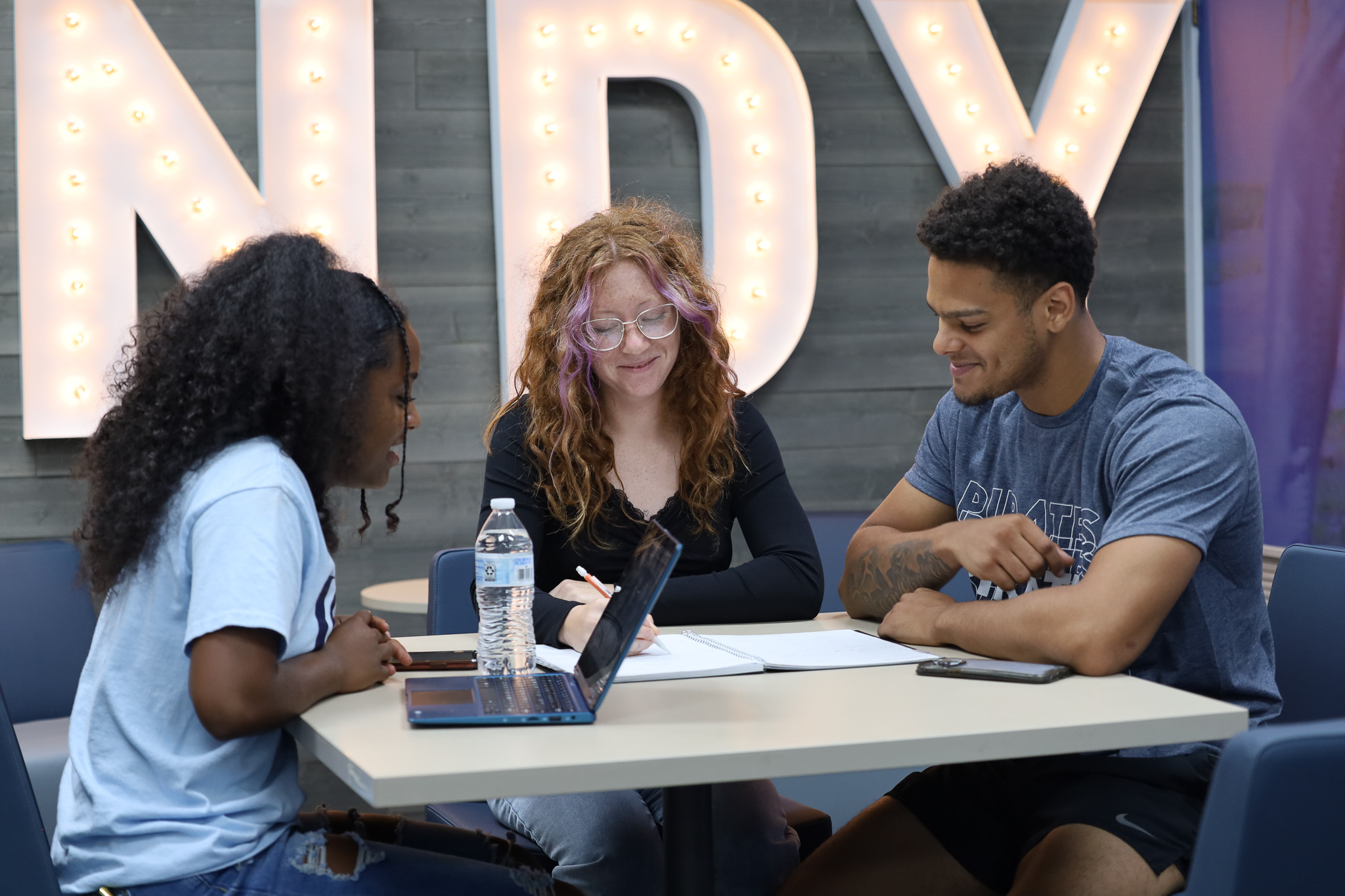 three students sitting at a table studying